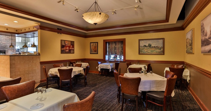Interior, dining area, white cloth tables for four and two, framed paintings