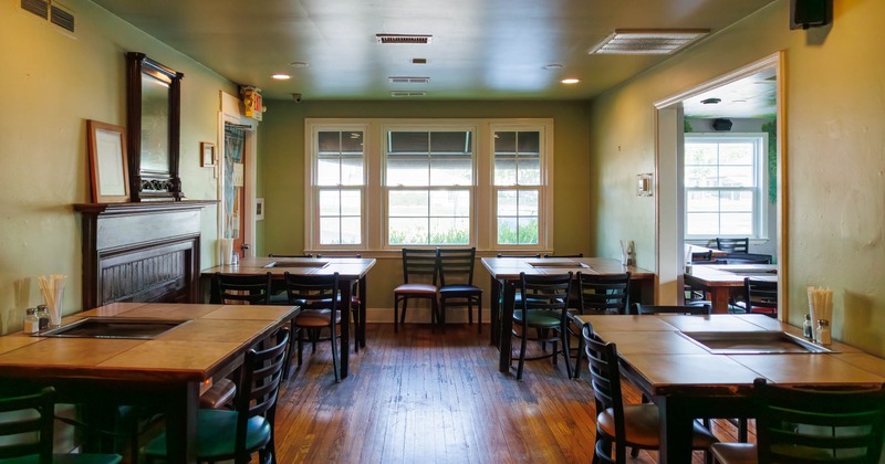 Restaurant dining area with wooden tables, chairs, and a large window