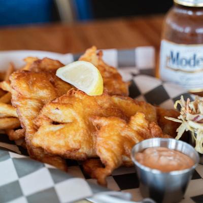 Beer Battered Flounder served over a bed of fries with coleslaw and a sauce.