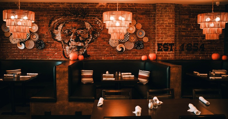 Interior, seating booths with tables ready for guests, murals on a red brick wall