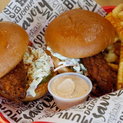 Hot chicken sandwich, with coleslaw, sauce, pickles, and fries.
