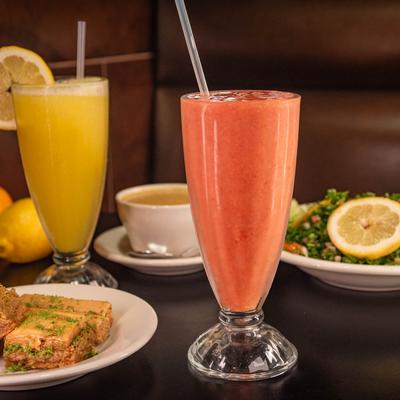 Strawberry smoothie with orange juice, baklava dessert, tabbouleh salad, and lentil soup.