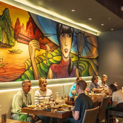 People dining beneath colorful wall mural.