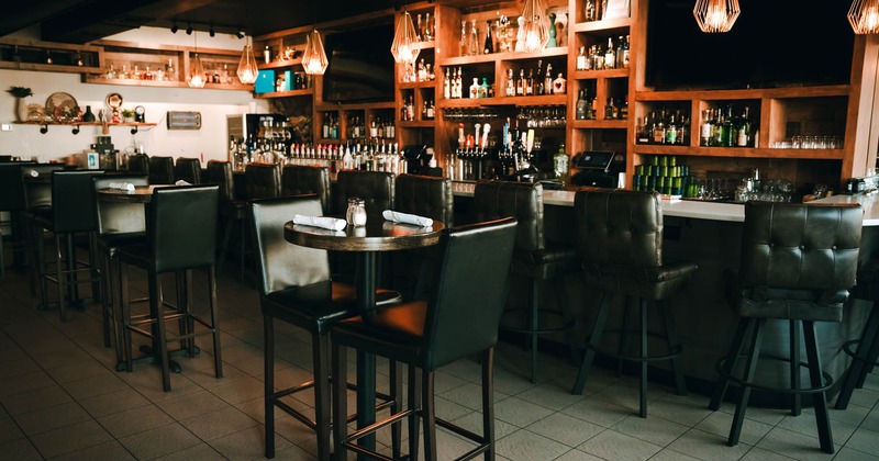 Interior, high seating area, tables for two, marble top bar with stools, large wine shelf