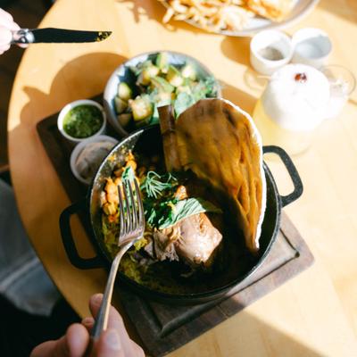 A hand holding a fork up to a meal.