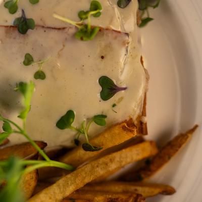 Hot ham and cheese sandwich served with fries, close up.
