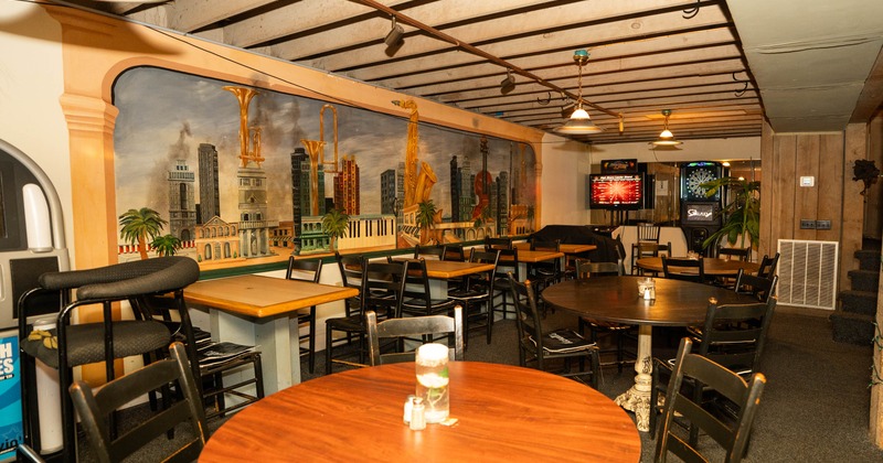 Indoor dining area featuring a cityscape mural, wooden tables, and black chairs