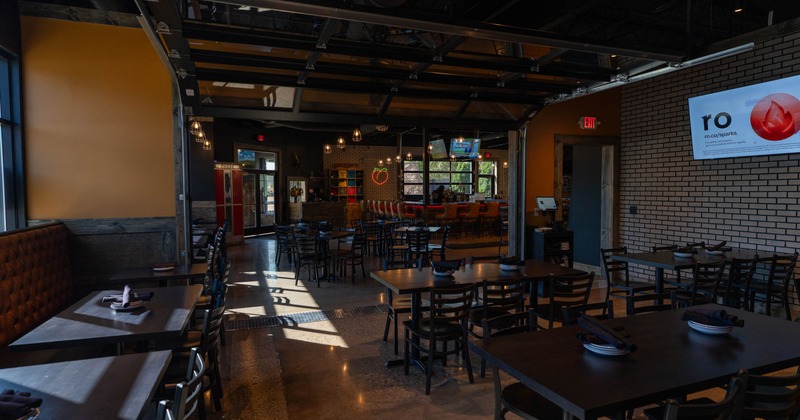 Interior of a spacious, modern restaurant with rows of tables and a bar area