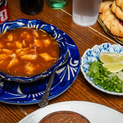 Menudo soup with hominy served with lime, cilantro and onions on the side.
