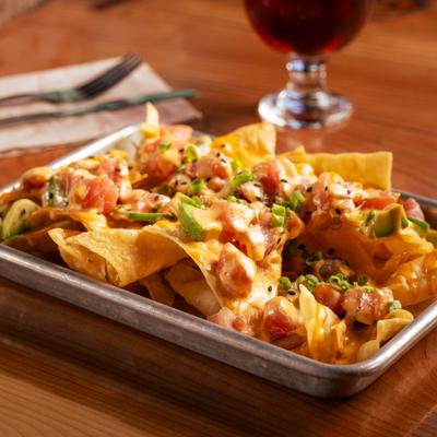 Tuna poke nachos with sriracha aioli, avocado, scallions, and sesame seeds.