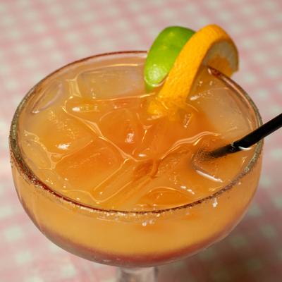 Orange cocktail with lime and orange slice garnish.