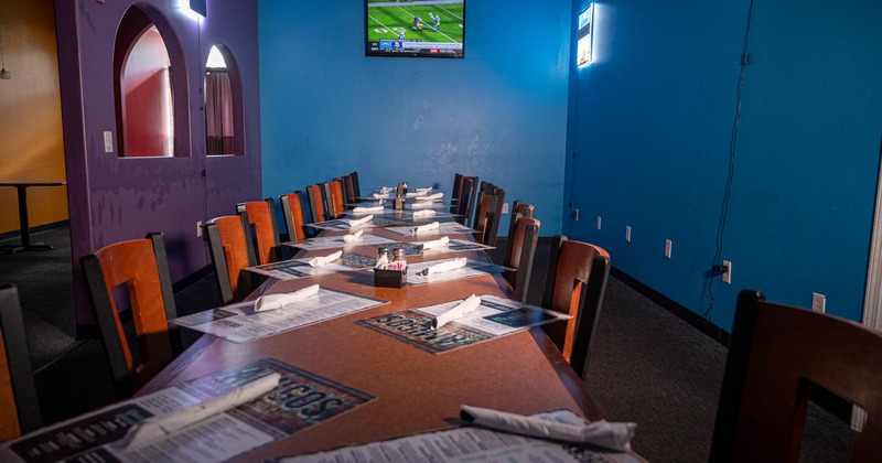 Interior, long table setup, ready for guests, carpet flooring, TV on the wall, neon sign