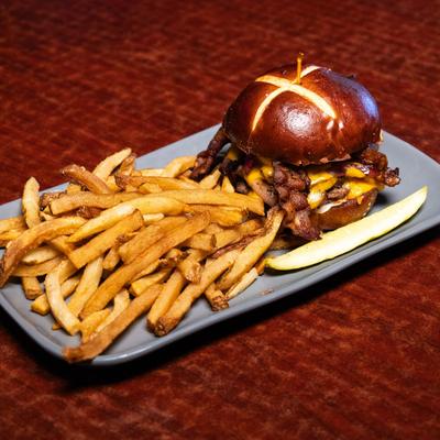 Beer Cheese Smash Burger served with a pickle and fries.