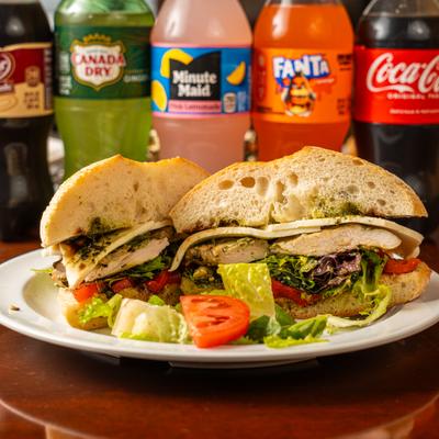 Chicken sandwich with lettuce, tomato, cheese, and pesto sauce.