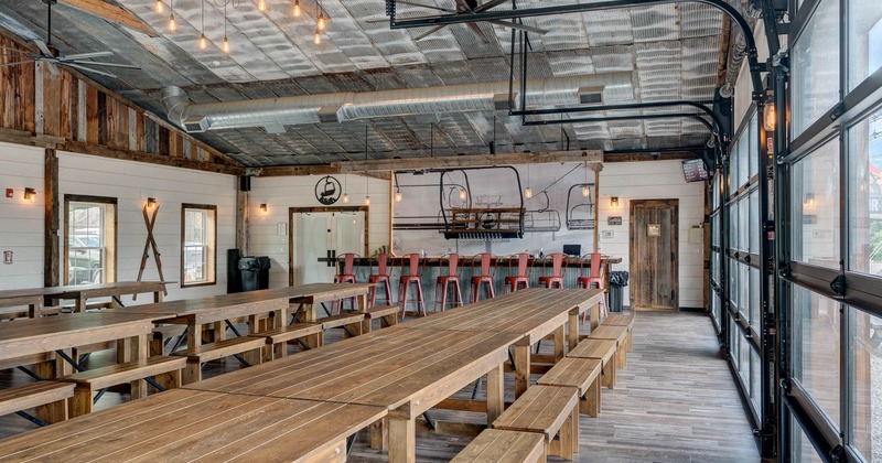 Interior, tables and benches in seating area with bar behind