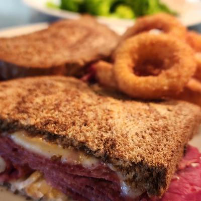 Reuben sandwich on grilled rye, a side of onion rings.