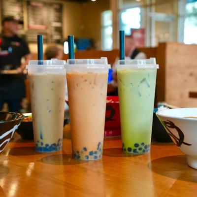 Three cups of colorful bubble tea sit on a restaurant table.