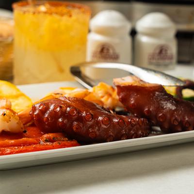 Grilled octopus and shrimp served with roasted red pepper and a cocktail.