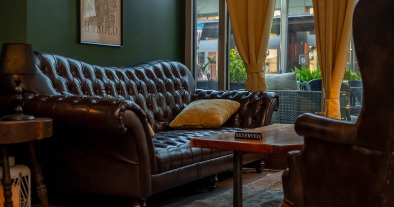Interior, brown leather vintage sofa, window, orange curtains tied up, coffee table