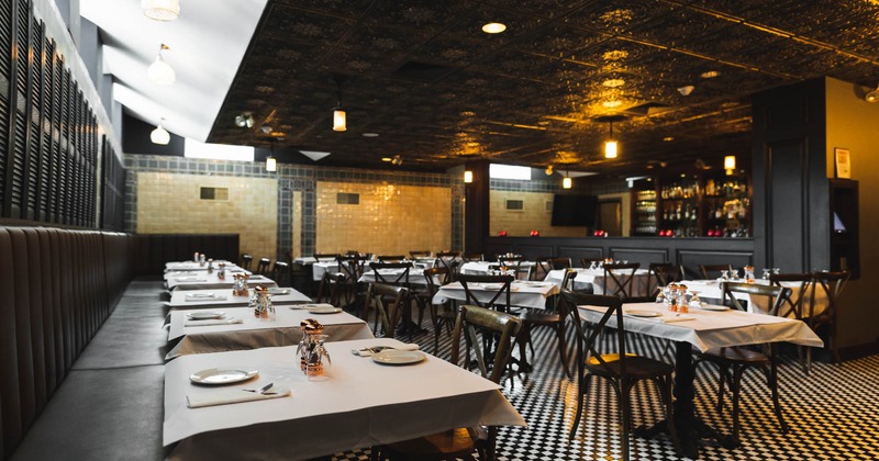 Interior, long banquette bench, tables and chairs, square patterned black and white floor tiles