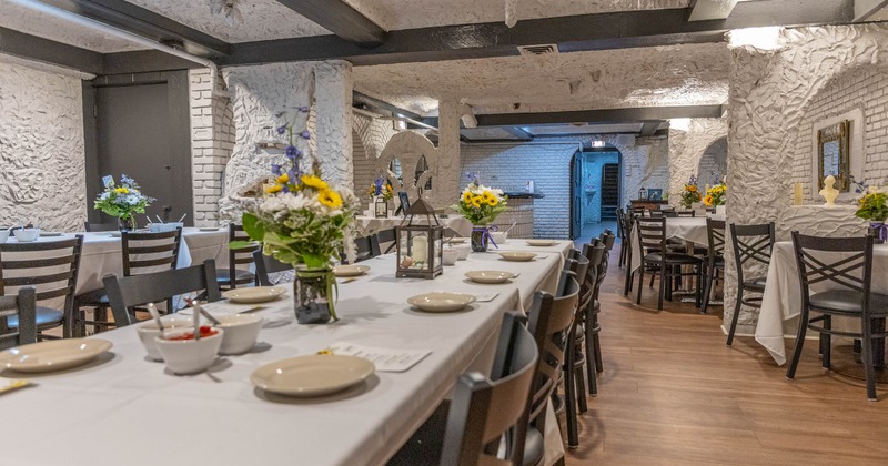 Interior, dining area, wooden beams, and long tables set for a banquet with flower arrangements