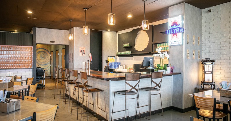 Interior, wooden top bar with bar stools, neon sign, beer taps, drinks on shelves