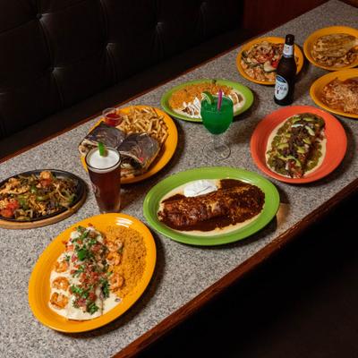 A colorful spread of Mexican dishes and drinks covers a restaurant table.