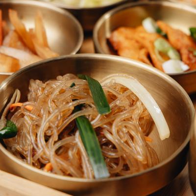 Stir-fry glass noogles served in a brass bowl on a wooden platter, close-up.