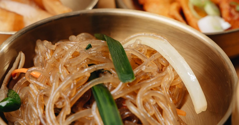 Korean stir-fried noodle dish served in a traditional brass bowl