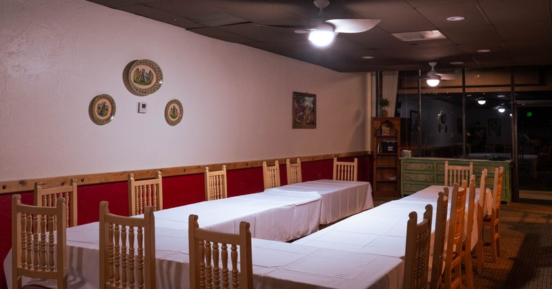Dining room with U-shaped table setup, white tablecloths, and wooden chairs