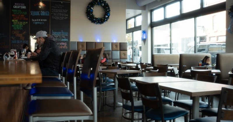 Interior, bar and seating area with tables, chairs and booths along the windows