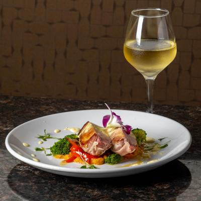 Plated gourmet meat dish served with broccoli and white wine.