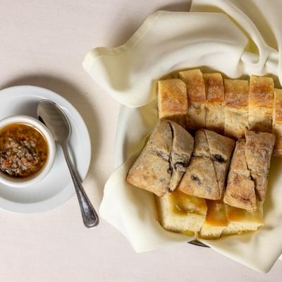 Basket of sliced bread served with a small dish of dip with a spoon.