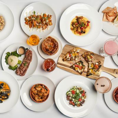 Assortment of dishes served on the table alongside cocktails, overhead view.