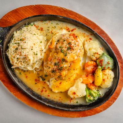 Stuffed Catfish served in a skillet with sides of pasta and vegetables.