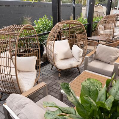 Outdoor wicker lounge chairs with cushions on patio.
