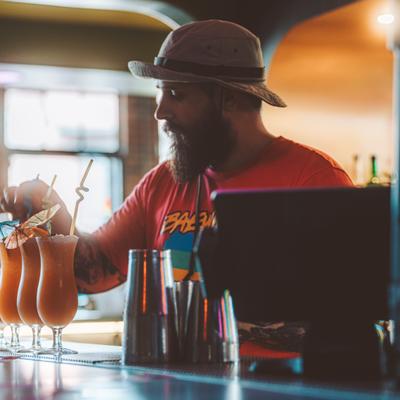 A bartender decorating cocktail glasses behind counter