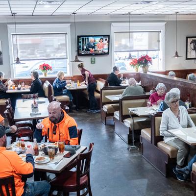 A busy diner, patrons are seated and eating meals.