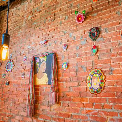 Decorated brick wall with framed art and hanging ornaments.