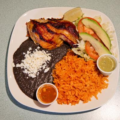 Pacos Chicken served with rice, refried beans, avocado, salad and two cups of salsa.