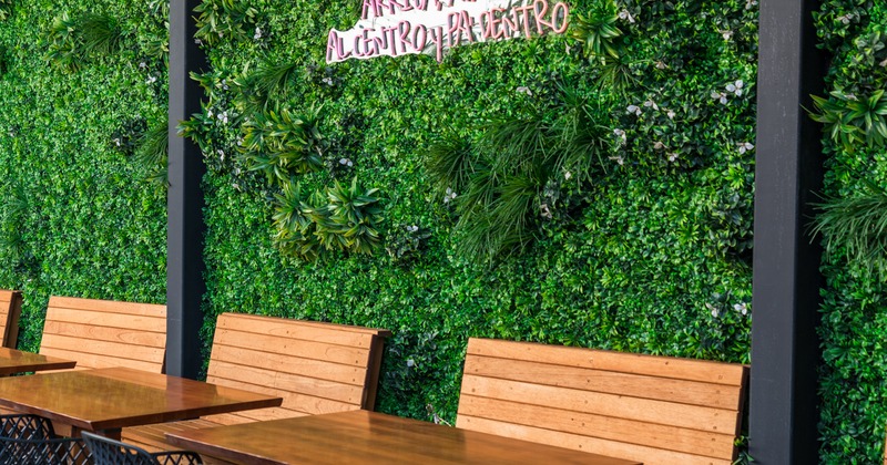 Exterior, benches by the green plant wall, light sign on