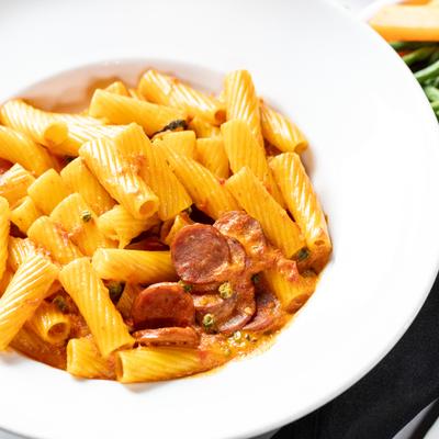 A dish of rigatoni pasta with a tomato and sausage sauce.