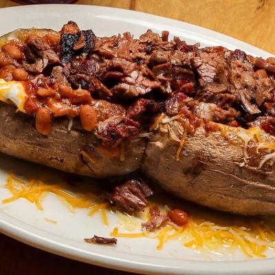 Loaded BBQ baked potato topped with brisket, beans, cheese, and sour cream.