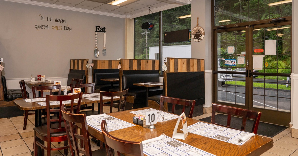 Interior of a cozy restaurant with wooden tables and black booths