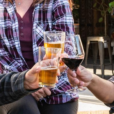 Three people clinking glasses of beer and wine.
