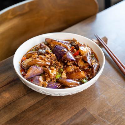 Eggplant and minced pork in a spicy garlic sauce, served on a wooden table with chopsticks.