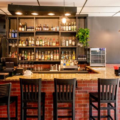 Interior, Front view of a bar with bar chairs and drinks displayed on bar shelves.