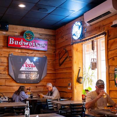 A group of diners sitting at tables in the restaurant with signs on wooden walls.