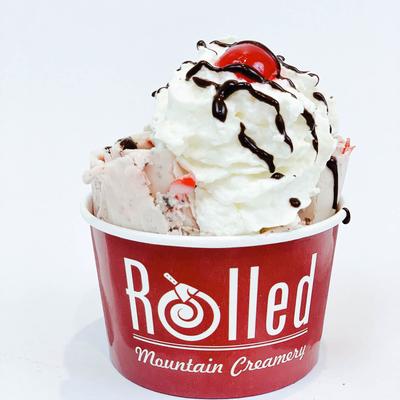 Vanilla ice cream with chocolate drizzle and cherry.