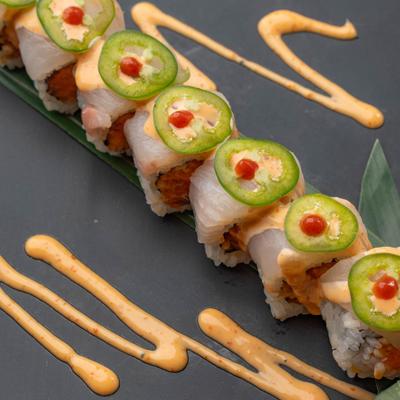 Spicy Tuna Jalapeno Roll served on a platter drizzled with sauce.